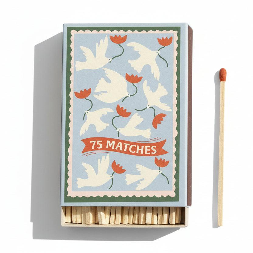 Matchbox with decorative design of doves and flowers, accompanied by a single matchstick.