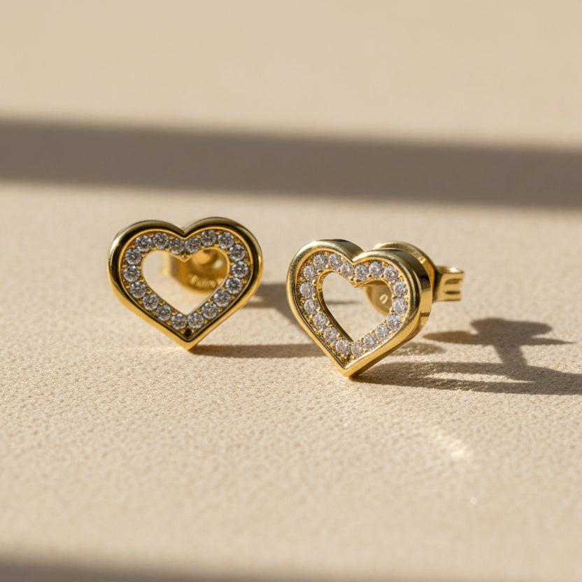 Heart-shaped gold earrings with clear gemstones on a white background