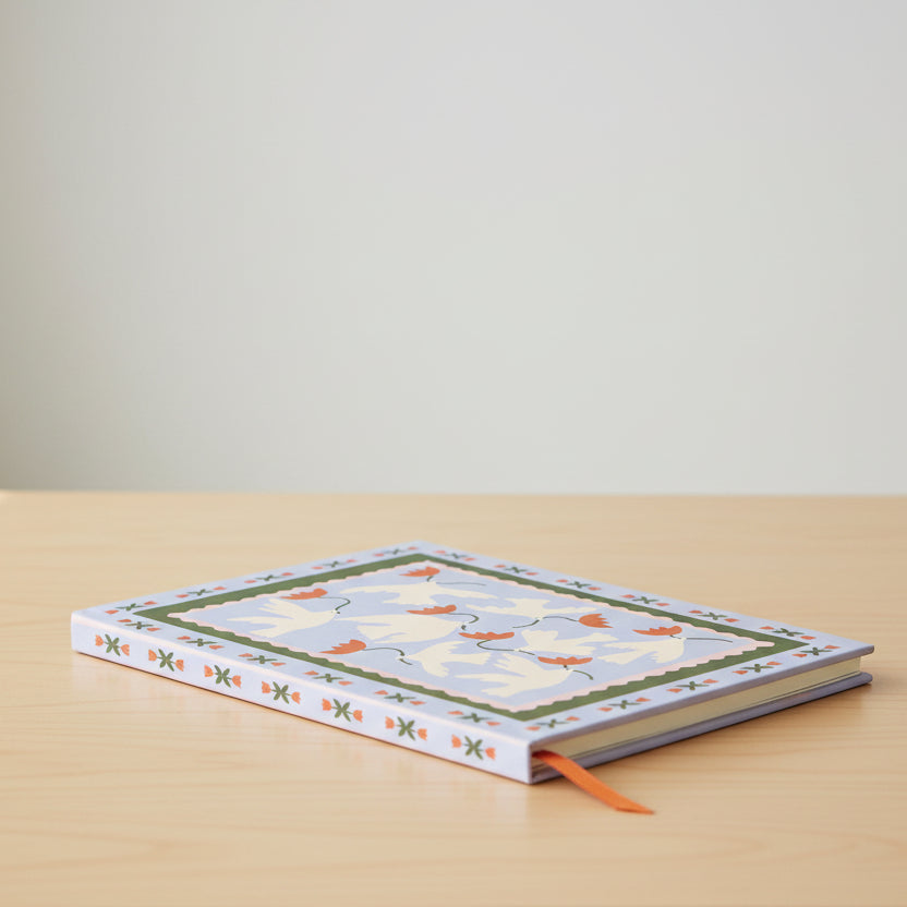 Notebook with a decorative cover featuring doves and flowers on a white background