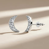 Silver moon-shaped earrings with embedded stones on a white background