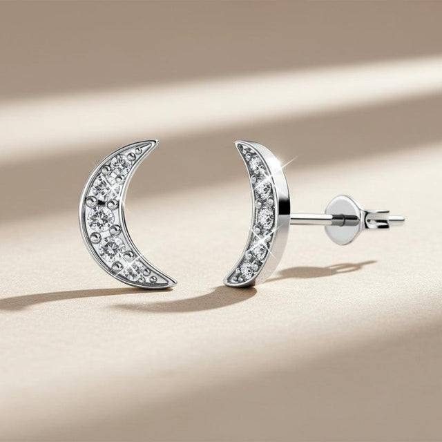 Silver moon-shaped earrings with embedded stones on a white background