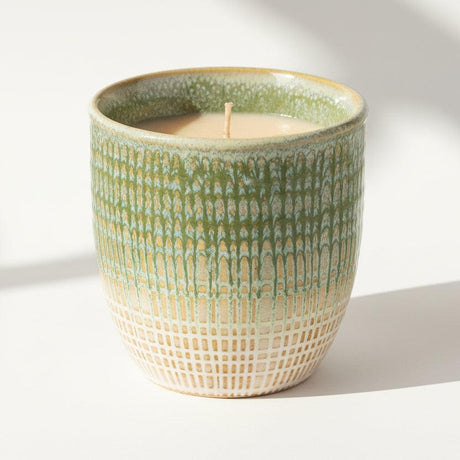 Green textured ceramic candle on a white background