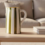 Ceramic pitcher with green and white stripes on a white background