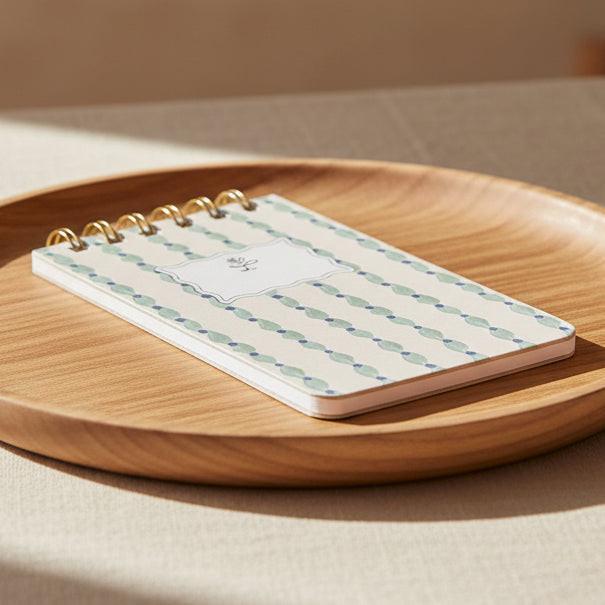 Notebook with a decorative cover featuring blue and green patterns on a white background
