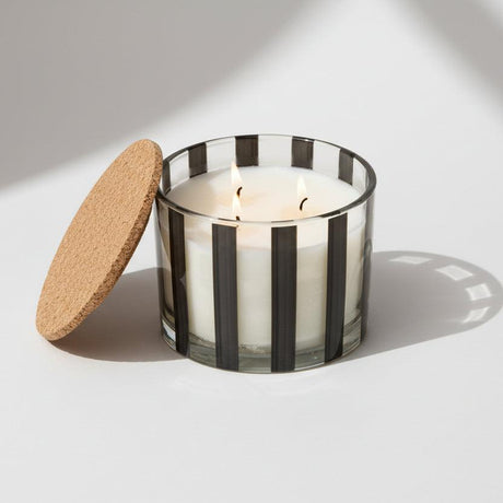 Elegant striped luxury candle casting a warm, inviting glow in an upscale setting