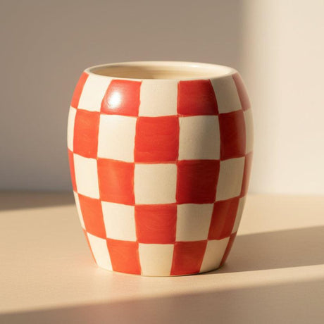 Red and white checkered ceramic cup on a white background