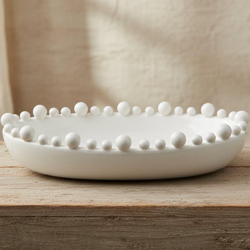 White decorative bowl with raised spherical elements on a white background