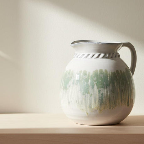 White ceramic pitcher with green and gray glaze on a white background