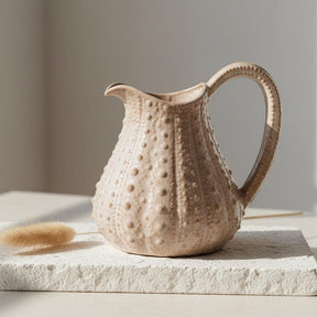 Decorative ceramic pitcher with textured surface on a white background