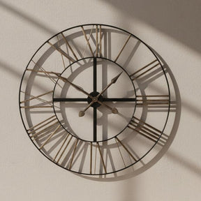 Large round wall clock with metallic Roman numeral markers on a white background
