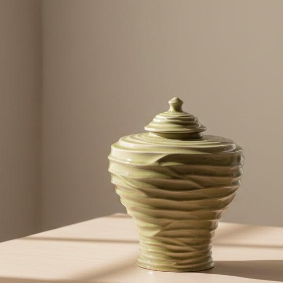 Beige ceramic jar with ribbed design and lid on a white background