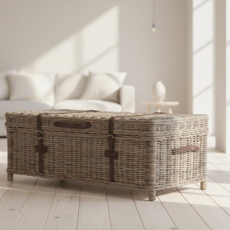 Wicker coffee table in a bright living room with white sofa and large windows.