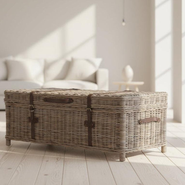 Wicker coffee table in a bright living room with white sofa and large windows.