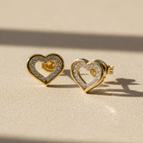 Heart-shaped gold earrings with clear gemstones on a white background