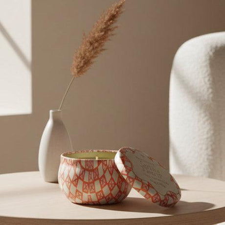 Candle in a patterned tin with lid on a white background
