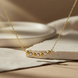 Gold necklace with small diamonds on a beige surface