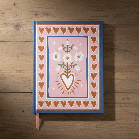 Notebook with heart and floral design on a pink background